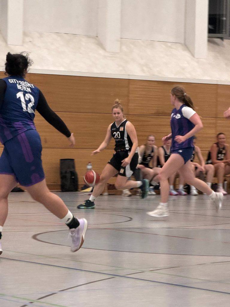 Zweikampf im Spiel: Gegnerin am Ball, Spielerinnen von CITY Basket Berlin laufen mit