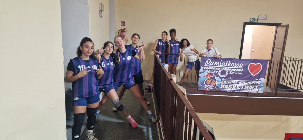 WU16 von CITY Basket Berlin – Team mit Peace-Zeichen auf der Treppe vor dem Banner von Kotwica Kołobrzeg